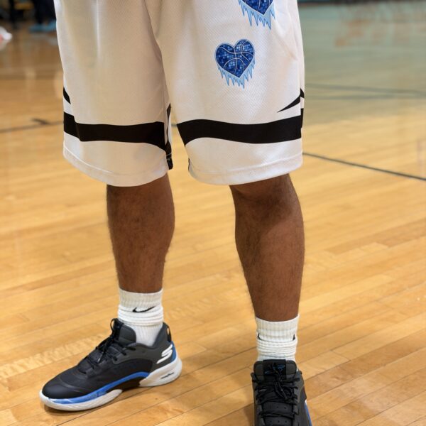 Basketball player wearing white shorts and black sneakers on court.